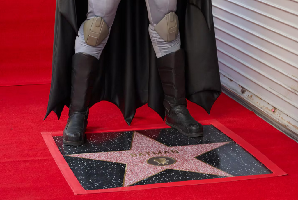 Un actor que se hace pasar por el personaje de Batman se arrodilla sobre su recién inaugurada estrella en el Paseo de la Fama de Hollywood después de una ceremonia en honor al superhéroe. (ALLISON DINNER/EFE)