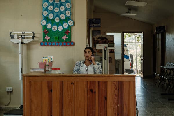Una mujer, sentada detrás de un escritorio, habla por celular en un ambiente de la clínica maternoinfantil.