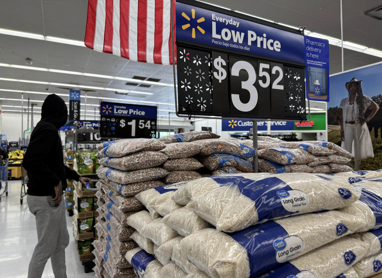 Interior de una tienda Walmart con bolsas de arroz y frijoles; los carteles de precios muestran $3,52 y $1,54.