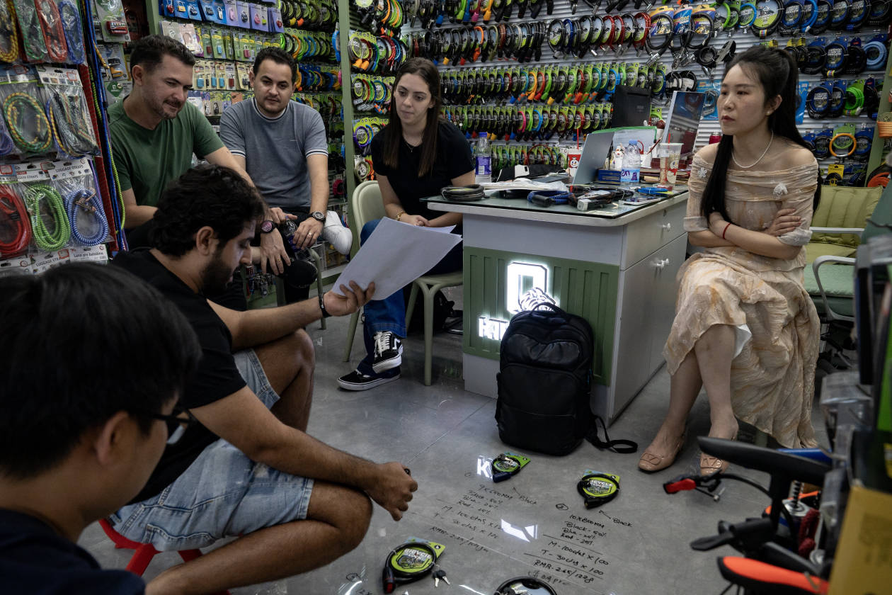 Compradores extranjeros negociando con el propietario de una tienda en un mercado chino.
