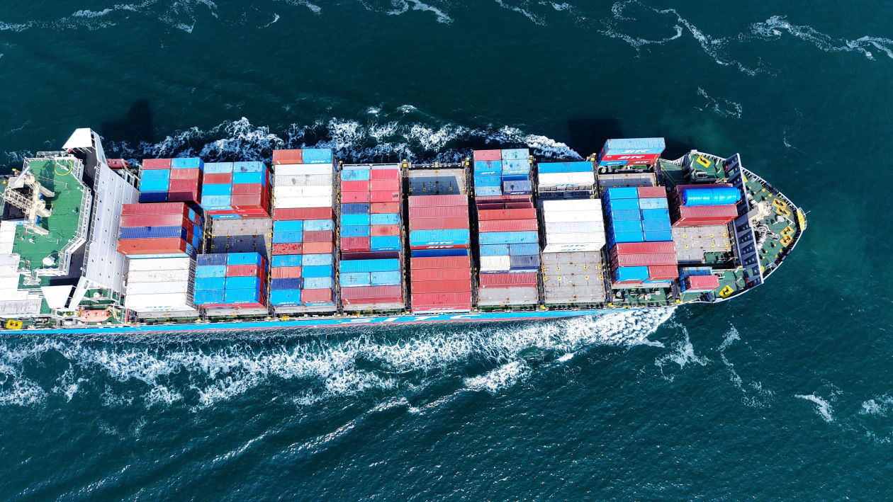 Vista aérea de un barco de carga que transporta muchos contenedores en el mar.