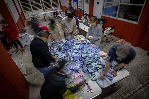Funcionarios electorales clasificaban boletas en una mesa de un edificio de oficinas.