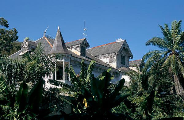Un edificio blanco en medio de un jardín de árboles.