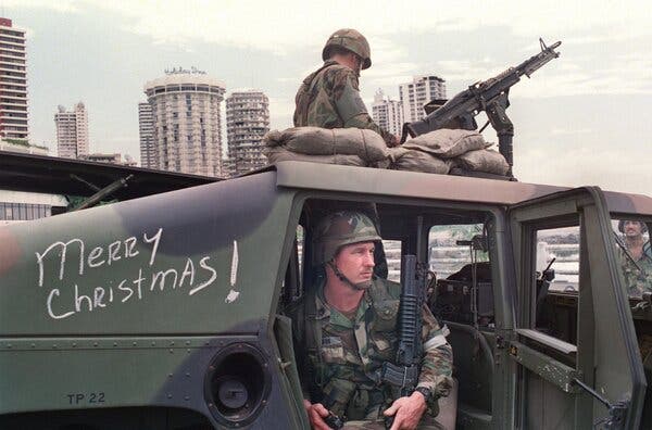 Soldados vestidos de camuflaje en un tanque frente a edificios altos en la ciudad de Panamá.
