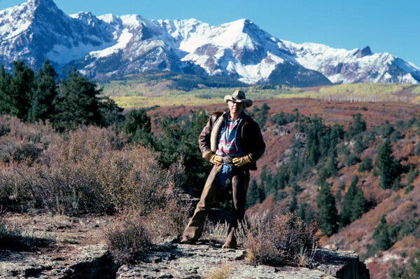 Ralph Lauren, con un sombrero de vaquero, de pie en un descampado con las Montañas Rocosas nevadas al fondo.