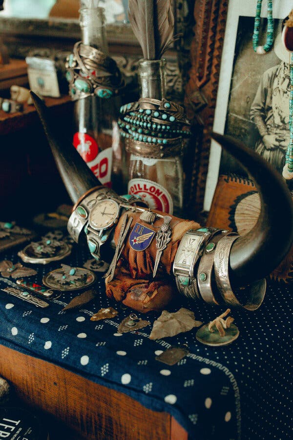 Una mesa con una cornamenta cubierta con relojes y pulseras. Otros accesorios descansan sobre la superficie.
