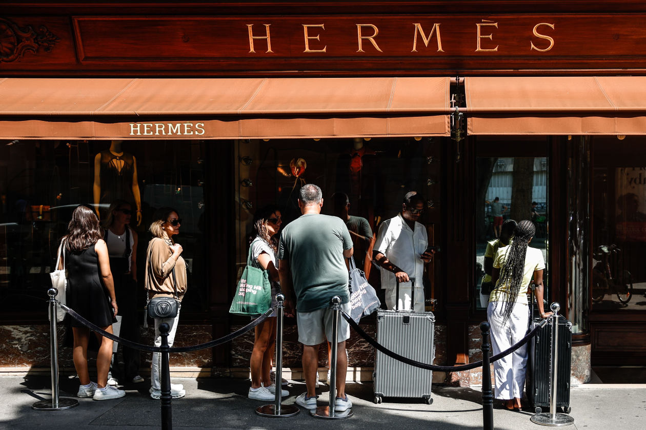 Personas haciendo fila afuera de una tienda de Hermès en París.