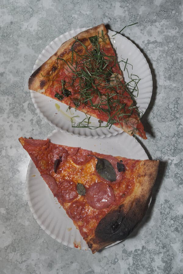 Dos pedazos de pizza sobre platos de papel.
