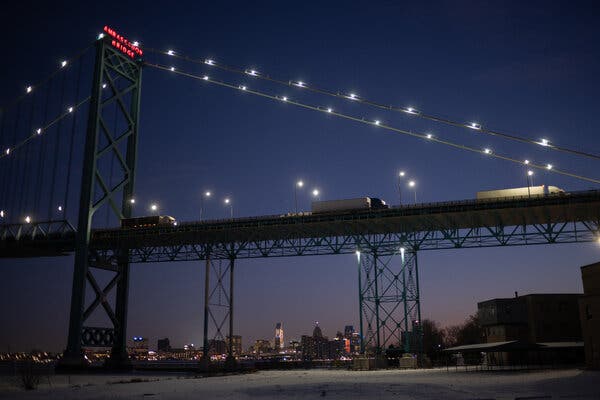 Camiones circulan por un puente elevado al anochecer.