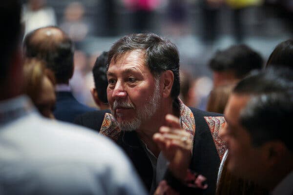 Un hombre con barba canosa, enfocado en una multitud borrosa.