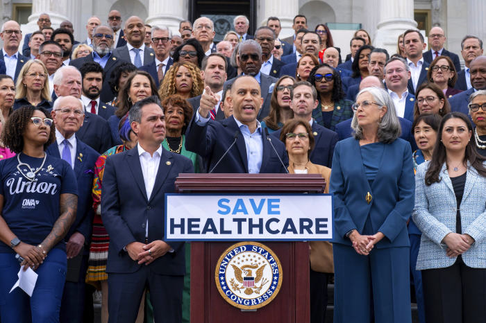 El líder de la minoría de la Cámara de Representantes, Hakeem Jeffries, habla en el Capitolio con otros miembros del Congreso detrás de él.