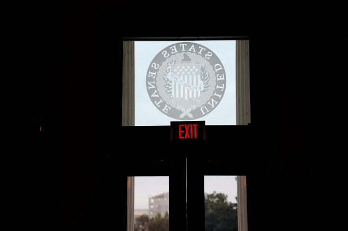 Una señal de salida iluminada sobre una puerta con el sello del Senado de los Estados Unidos.